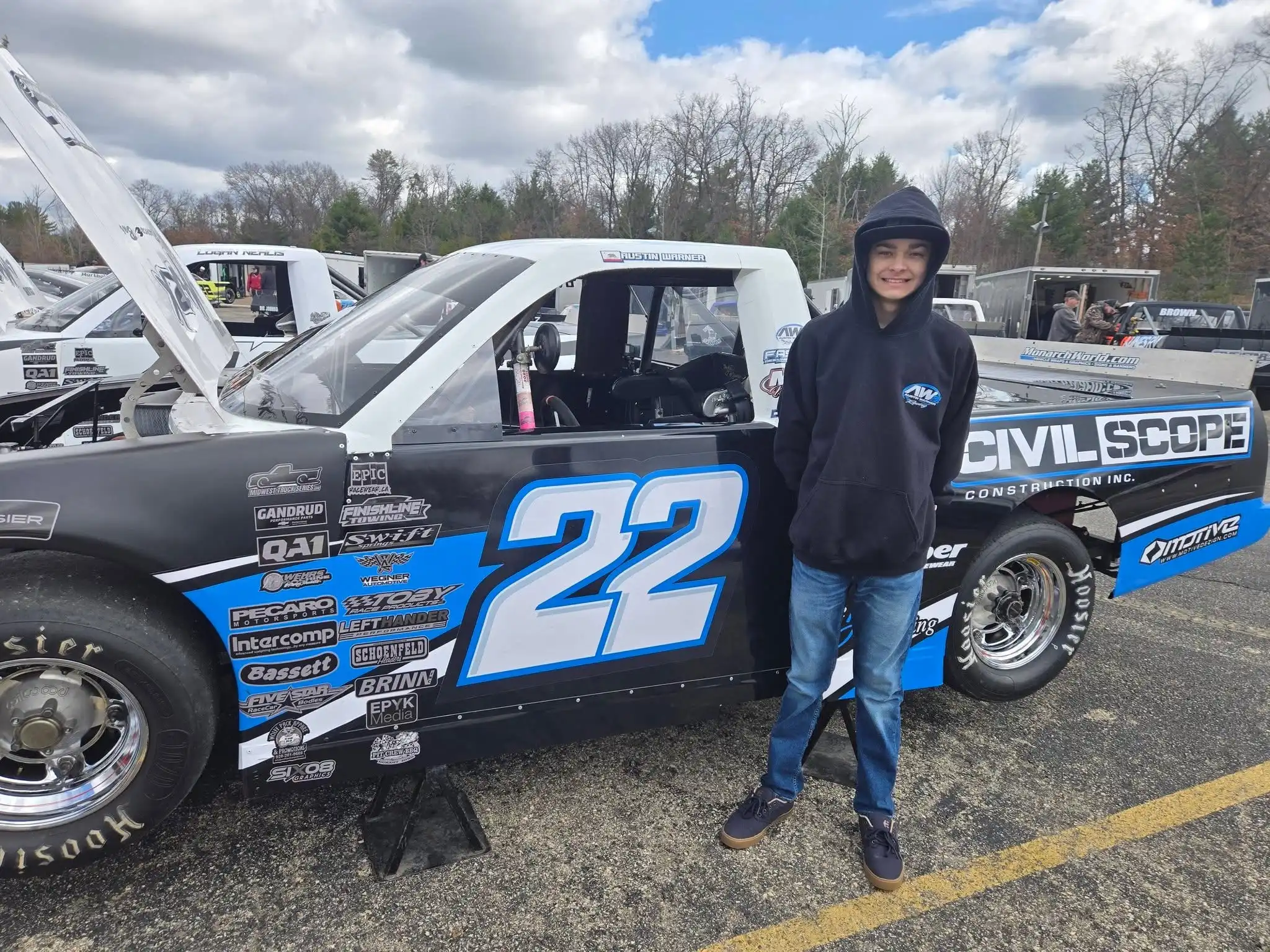 Austin Warner standing next to the number 22 race truck