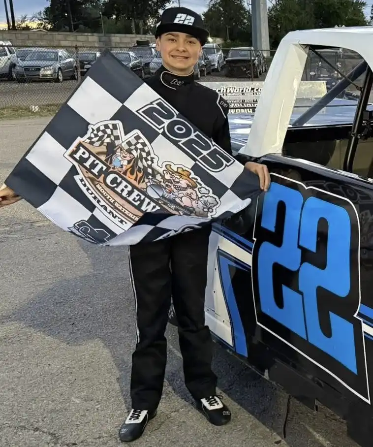 Austin Warner holding a checkered flag next to the number 22 truck