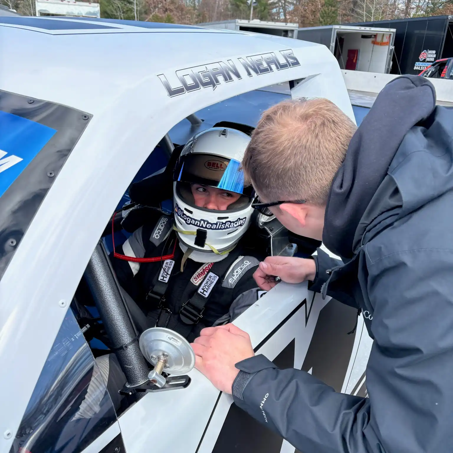 Bryce Miller talking with Logan Nealis while Logan sits strapped into the race truck